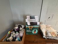 Terracotta pot box, stack of shrink-wrapped frames, burlap bags in wire basket, box of assorted paints and glues