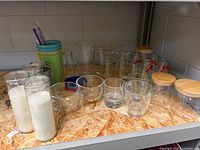 All items arranged on shelf showing glass drinkware, storage jars, candles, tumbler and accessories
