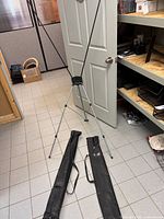 Assembled X-frame stand with two carry bags on floor
