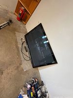 Front view of Panasonic 54-inch plasma TV with remote and power cord on floor