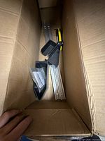 Boxed kit showing aluminum rails, plastic feet, strap, hardware bag and paperwork