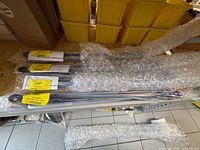 Four bubble-wrapped 24" pantograph arms with yellow REV labels visible
