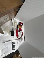 Full kit showing red webbing on retractor, buckle, hardware bag, manual