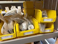 Yellow bins holding clear plastic bags of SEN bolt cutter mounting kit parts