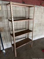 Front view of entire metal shelving unit showing four shelves and slotted uprights