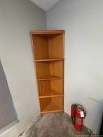 Full view of 4-tier oak corner shelf standing on floor