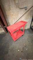 Full view of red Uline utility cart showing both shelves and casters