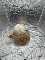 Front angled view of white Morning Pride helmet inside plastic face-shield bag, showing red reflective stripe and dirt