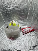 Top and front view of white firefighter helmet with visor wrapped and tag attached
