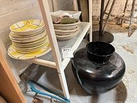 Shelf with stacks of Hycroft plates, beige bowls, white compote bowl, and black vase