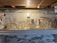 Shelf with multiple clear cut glass pieces including bowls, goblets, lamp