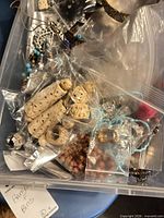 Top view of bin showing carved beige bangles, turquoise beads, assorted bagged components