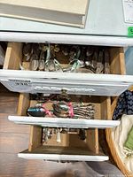Drawer containing multiple ribbon-tied bundles of flatware pieces