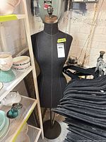 Front view of fabric-covered dress form with wood finial on metal stand