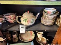 Shelf view with teapot, cups, plate stacks, creamer, sugar, pitcher
