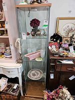 Front view of glass curio cabinet showing shelves and wood base/top