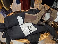 Multiple pairs of boots in basket with size tag