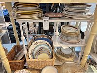 Multiple stacks of assorted plates and platters on shelving unit