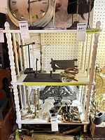 Front view of white three-tier wooden shelf with items on it