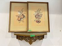 Front view of both framed prints resting on wall shelf