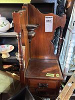 Front view of first wood telephone shelf showing turned supports, display platform, drawers