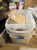 Stacked clear plastic bins containing wooden organizers and other items