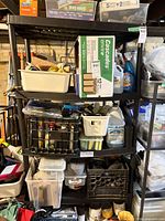 Front view of black plastic shelving unit with contents (not included) on four shelves