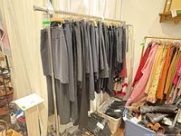 Rolling chrome garment rack with numerous metal hangers and storage bins beneath
