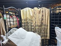 Overall view of black metal grid folding screen with textiles draped