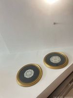 Two circular gold frames with lace medallions on dark ground