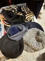 Bin of assorted hats, scarves visible including zebra scarf, black & grey berets