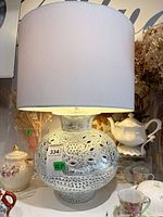 Full view of ceramic lamp with shade showing distressed silver-white finish and perforated design
