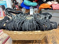 Basket filled with numerous black velvet hangers, showing overall contents.