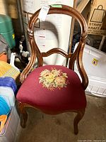 Front view of wood balloon-back chair with burgundy floral needlepoint seat