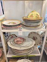Full lot on shelving showing stacks of plates, platters and covered butter dish