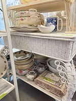 Shelf with stacked floral china plates, serving dishes, blue mug, gravy boat