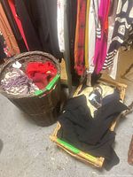 Tall cylindrical wicker basket with scarves inside and shallow wicker tray with black clothing
