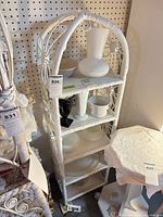 Full view of white wicker rattan shelf showing five shelves and arched top