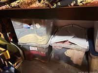 Two clear plastic bins filled with folded knit scarves and beanies under shelving