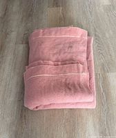 Folded pink wool blanket on wood floor
