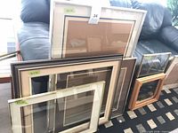 Group of six assorted frames leaning against sofa