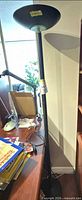 Full view of black torchiere floor lamp beside desk