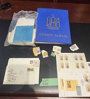 Overall lot showing blue album, plastic-bagged paper items, loose stamps and sheets