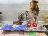 All items on countertop: snowman tray, leaf platter, two Santa glasses, stainless bucket with gift box on top, filigree ornaments