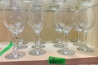 Front view of all twelve clear glass wine goblets on shelf