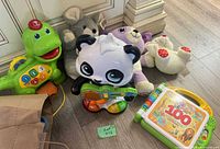 Group shot of all toys including green dinosaur, panda, 100 Animals book, plush mouse, plush dog, plush bunny