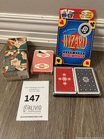 Lot overview showing Wizard card game box, patterned box, tuck box deck, clear case with two decks
