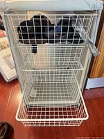 Front view showing three of four white wire baskets in metal frame