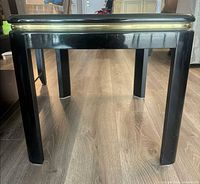 Front view of square black glossy end table showing gold band and four legs