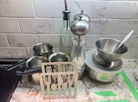 Group view of entire lot showing pots, bowls, cups, grinders, oil dispenser, flatware holder